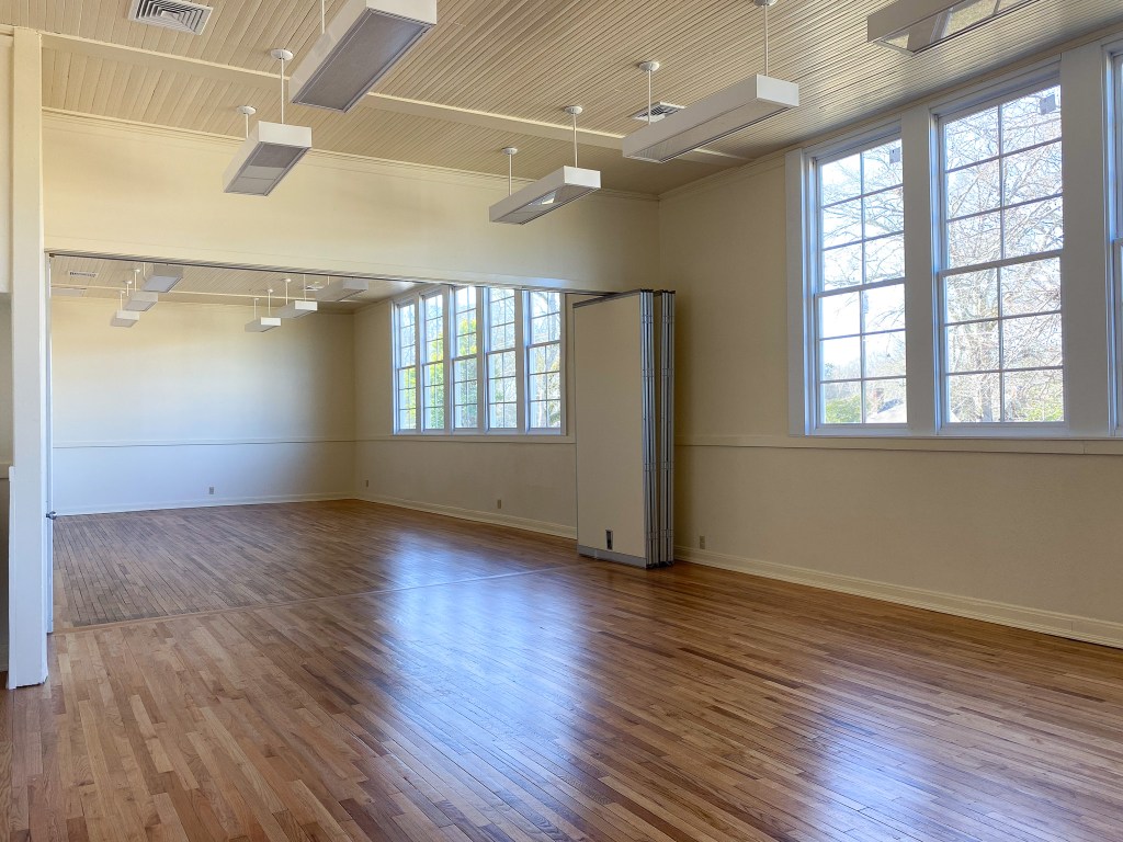 Image of a large room with wooden floors and nice windows that let in natural light.
