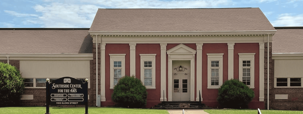 A brick building with white columns and a triangular pediment stands behind a sign that reads “Southside Center for the Arts, 1103 Glenn Street.”